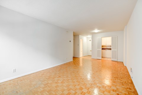 an empty living room with a wood floor and white walls